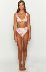 Front view of high-waisted bikini bottoms in a pink orange yellow wavy sun print, with a matching tie-front bikini top