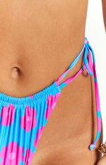 Close-up of the side tie detail on a blue and pink floral bikini bottom with a ruched waistband