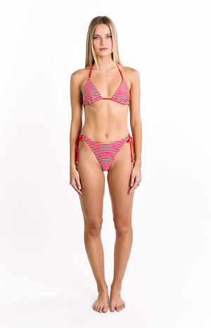 Our model wears bikini bottoms featuring thin horizontal stripes in bright red and white. The bottom is a minimal low-rise style with a V-shaped front and adjustable red string tie closures at the hips each finished with a small metallic accent.