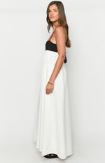Side view of a black and white contrast maxi dress with thin spaghetti straps and a flowy white skirt
