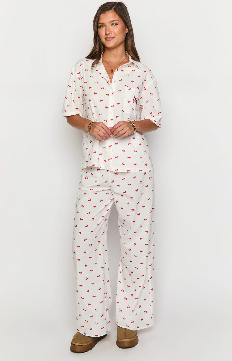 Front view of a white short sleeve collared pajama shirt with red cherry print, chest pocket, and BB logo