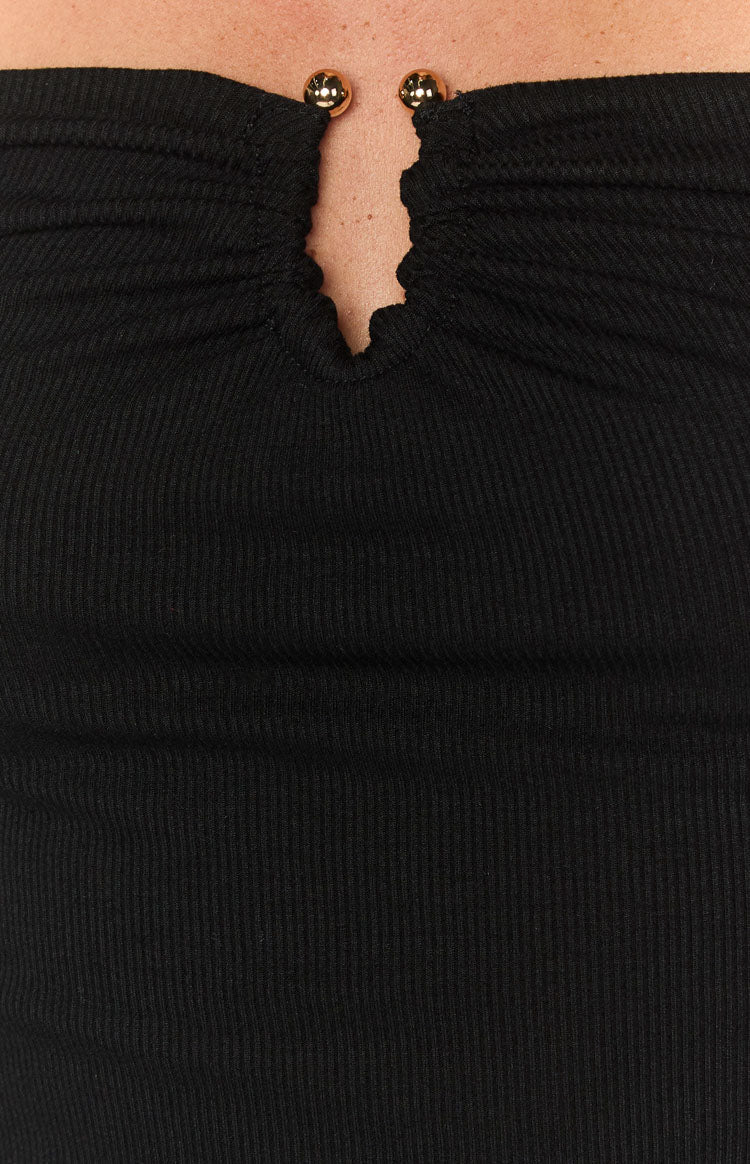 Close-up of the black ribbed knit top's ruched V-neckline with two gold sphere details