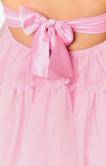 Close-up of a large pink satin bow tied at the back of the mini dress, above gathered pink tulle