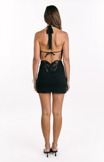 Rear view of a black mini dress with a halter neck tie, low scoop back, and sequin butterfly detail