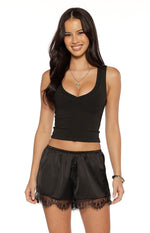 Black satin shorts with an elasticated waist and wide black lace trim along the hem