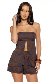 Front view of a brown strapless longline top with blue floral pattern and a deep front split revealing the midriff