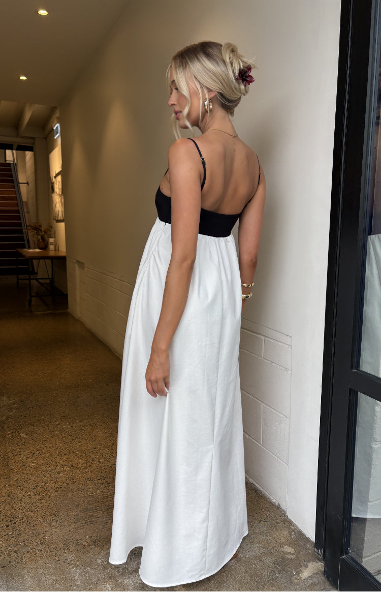 Rear-side view of a black bodice with thin spaghetti straps and a low back, flowing into a gathered white maxi skirt