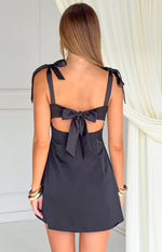 Rear view of a black mini dress with tie-up shoulder straps and a large back bow detail with cutouts
