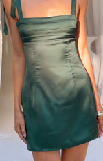Close-up of a green satin mini dress with a square neckline, tie straps, and pleated bodice detail