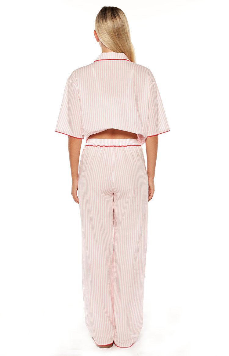 Rear view of pink and white striped wide-leg pajama pants with red trim on the elasticated waistband and hem