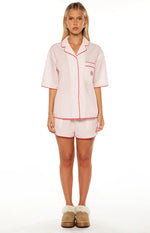 Full length view of a pink and white striped pajama set with red piping, including a short sleeve shirt and matching shorts