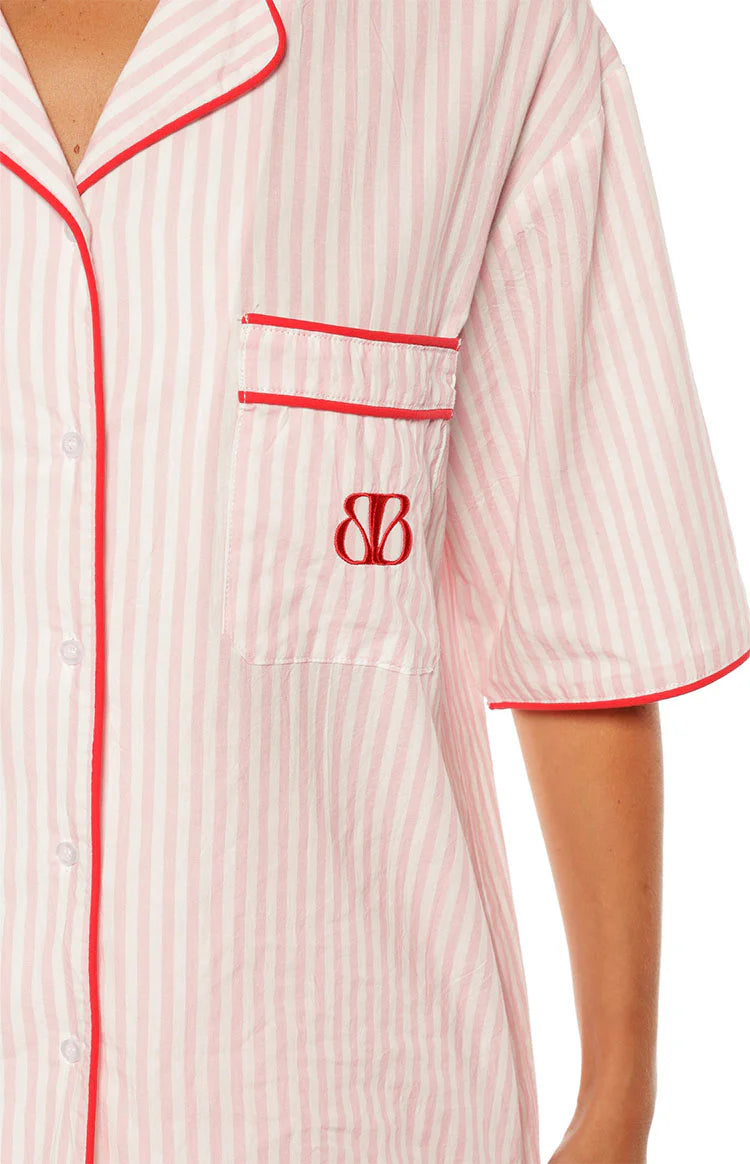 Close-up of the pink and white stripe pajama shirt showing the red embroidered logo on the chest pocket and red piping