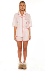 Pink and white striped pajama shorts with red piping, paired with a matching short sleeve button-up top