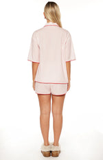 Rear view of pink and white striped pajama shorts and matching short sleeve top with red piping
