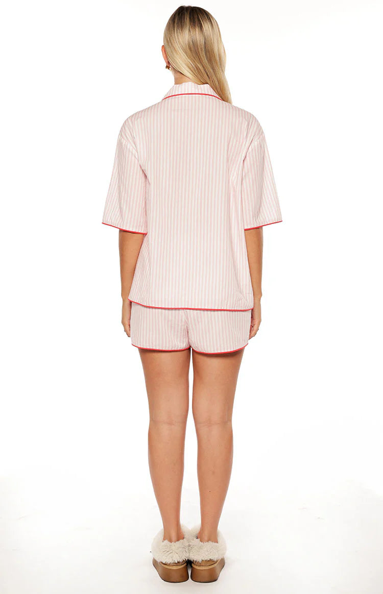 Rear view of pink and white striped pajama shorts and matching short sleeve top with red piping