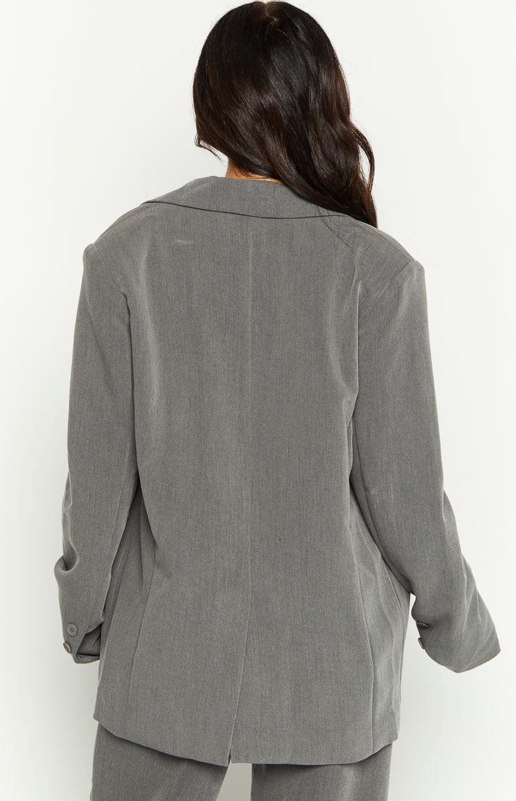 Side view of a grey double-breasted blazer with wide lapels, long sleeves, and buttoned cuffs