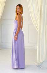 Side profile of a lilac crepe maxi dress with a structured bustier bodice, thin spaghetti straps, and a flowing skirt