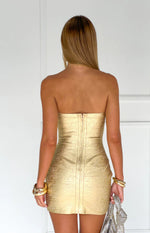 Rear view of a gold bandage strapless mini dress with an exposed zipper down the back