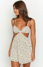 Close-up of the cream mini dress showing the twisted bust, side cutouts, and blue floral print
