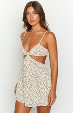 Close-up of the cream mini dress with blue floral print, showing the twisted bust and side cutouts