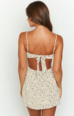 Rear view of the cream floral mini dress with a tie-back bust and cutouts at the waist