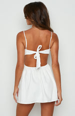 Rear view of a white mini dress showing the tie-back bodice, waist cutout, and elasticated skirt