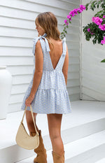 Rear view of a blue gingham floral mini dress with a deep V-back, tie-shoulder straps, and tiered skirt