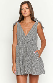 Black gingham mini dress with a deep V-neck, tie shoulders, gathered waist, tiered skirt, and side pockets
