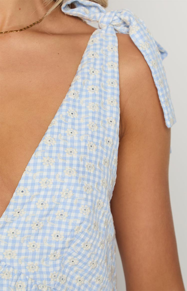Close-up of the light blue gingham mini dress with white floral embroidery and tie-shoulder straps