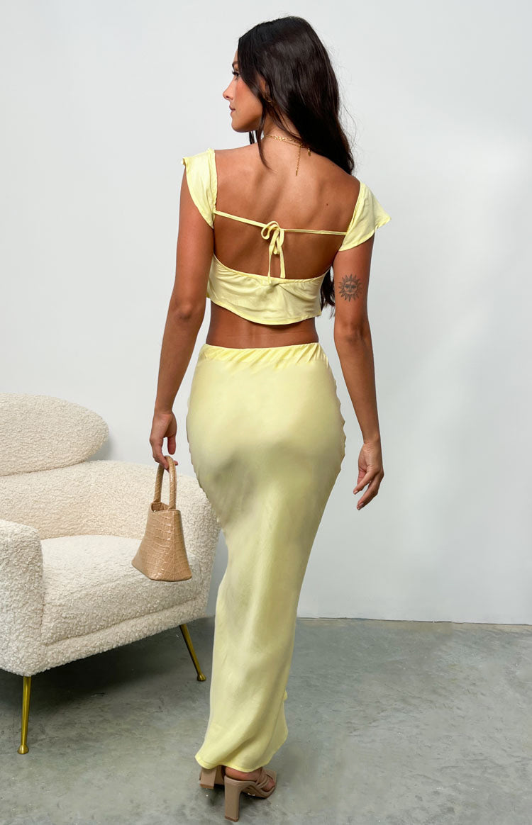 Back view of a yellow satin maxi skirt, fitted at the waist and hips, flowing to the floor