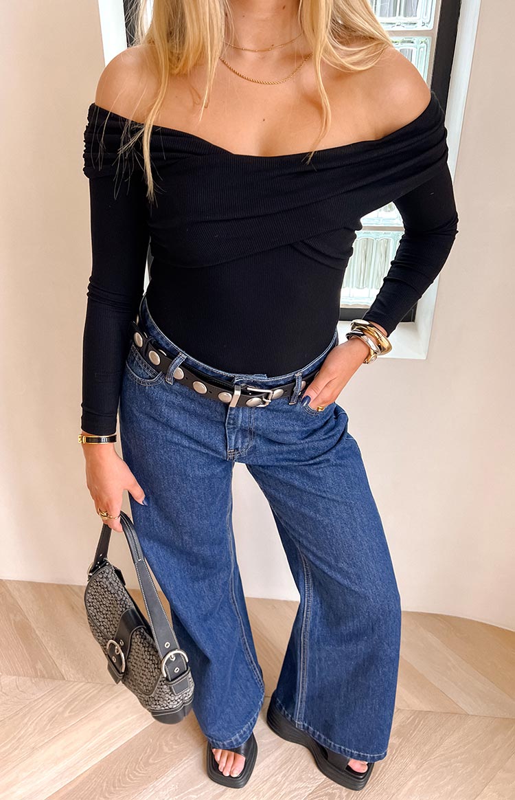 Close-up of the black ribbed off-shoulder bodysuit showing the crossover bust detail and ruched sleeves