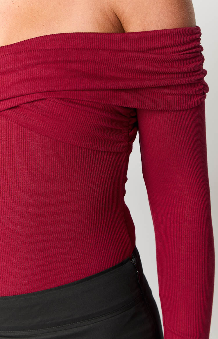 Red ribbed off-shoulder bodysuit with a close-up on the ruched neckline and fitted long sleeve
