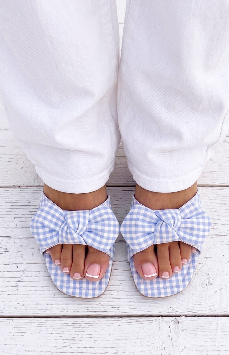 Overhead view of blue and white gingham check sandals with large fabric bows across the toes