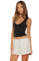 Close up of white shorts with black polka dots and a scalloped lace hemline styled with a matching top