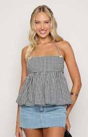 Front view of a black and white gingham halter top with a straight neckline, small bow details, gathered waist, and peplum hem