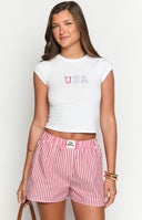 Model wearing a white baby tee with a USA graphic paired with a mid wash denim mini skirt