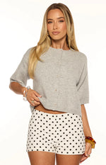 Close-up of a light grey short sleeve cropped cardigan with visible knit texture and ribbed hem