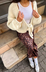 Rear view of a cream chunky knit cardigan with a deep V-back and large tie-up detail at the lower back