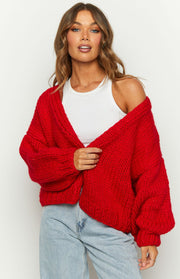 Angled view of a red chunky knit cardigan with an open front and ribbed cuffs