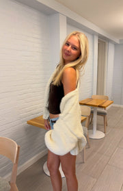 Side view of a cream chunky knit cardigan showing the relaxed fit and voluminous long sleeves
