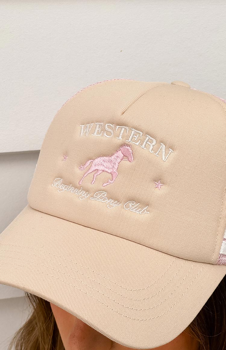 Close-up of a cream trucker cap with pink mesh detail, featuring pink embroidered 'Western' text, a jumping horse motif, and 'Beginning Pony Club' script.