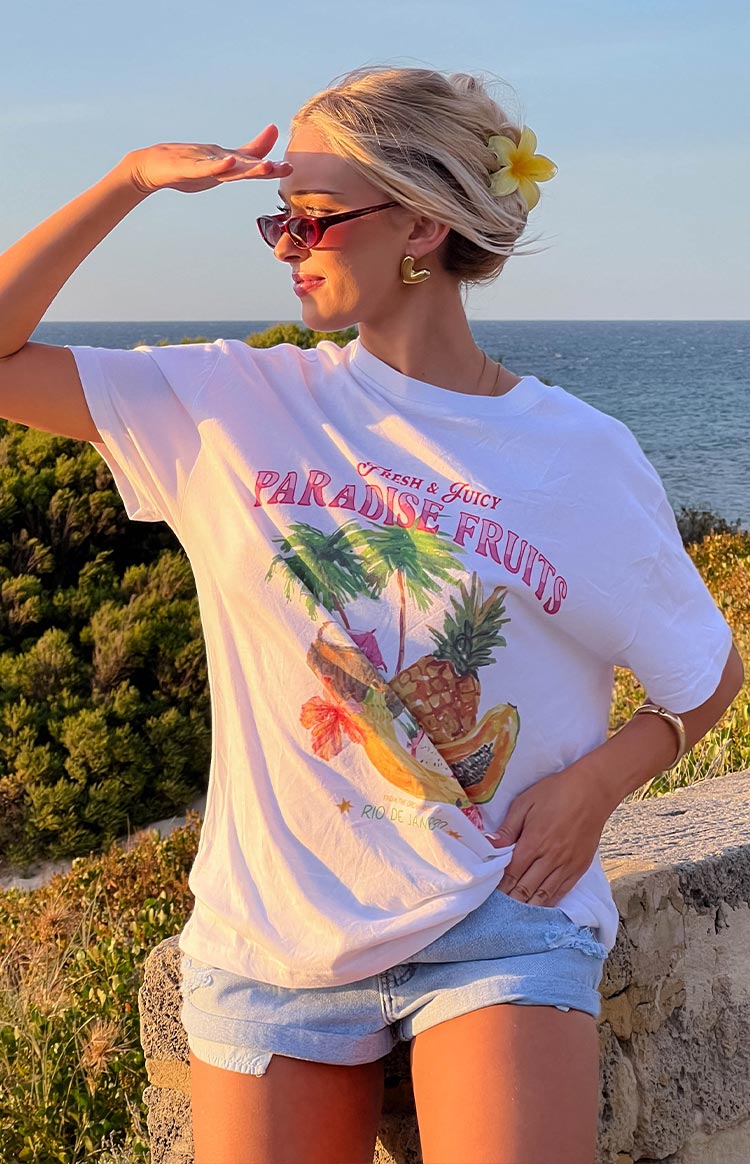 Side view of an oversized white tee with a colourful 'Paradise Fruits' graphic print featuring tropical fruits and palm trees