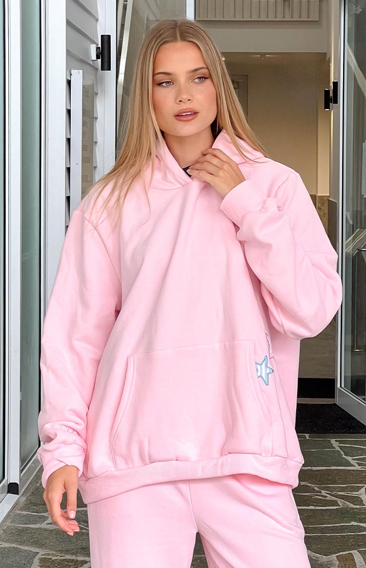 Pink oversized hoodie with a kangaroo pocket and a small blue star embroidery on the side