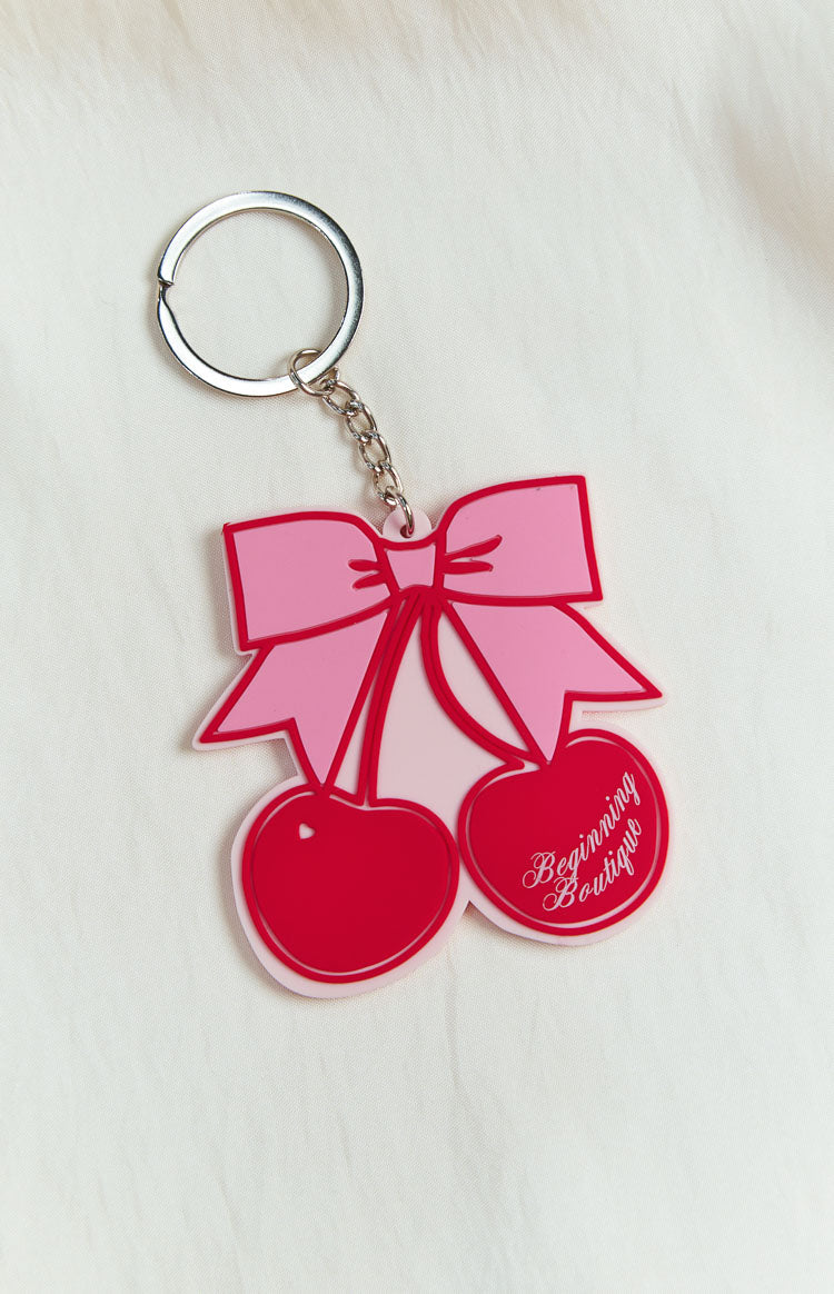 Pink bow and red cherry keyring with 'Beginning Boutique' text on the right cherry and a silver ring