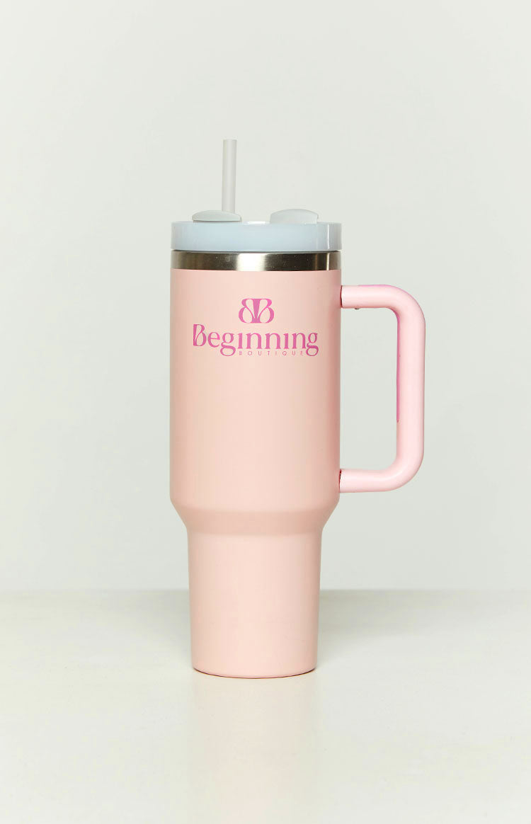 Front view of a light pink tumbler with a handle, light blue lid, pink straw, and pink logo