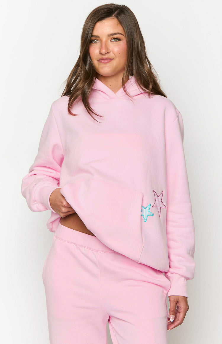 Front view of a pink hoodie showing the large kangaroo pocket with embroidered blue and pink stars