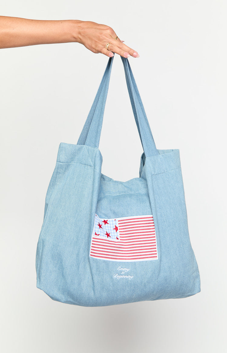 Model wearing a denim tote bag with a red and blue USA flag applique