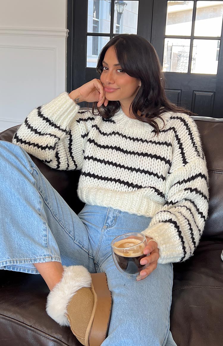 Close-up of the thick white chunky knit sweater with black horizontal stripes across the body and sleeve