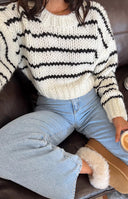 Close-up of the thick white chunky knit sweater with black horizontal stripes across the body and sleeve