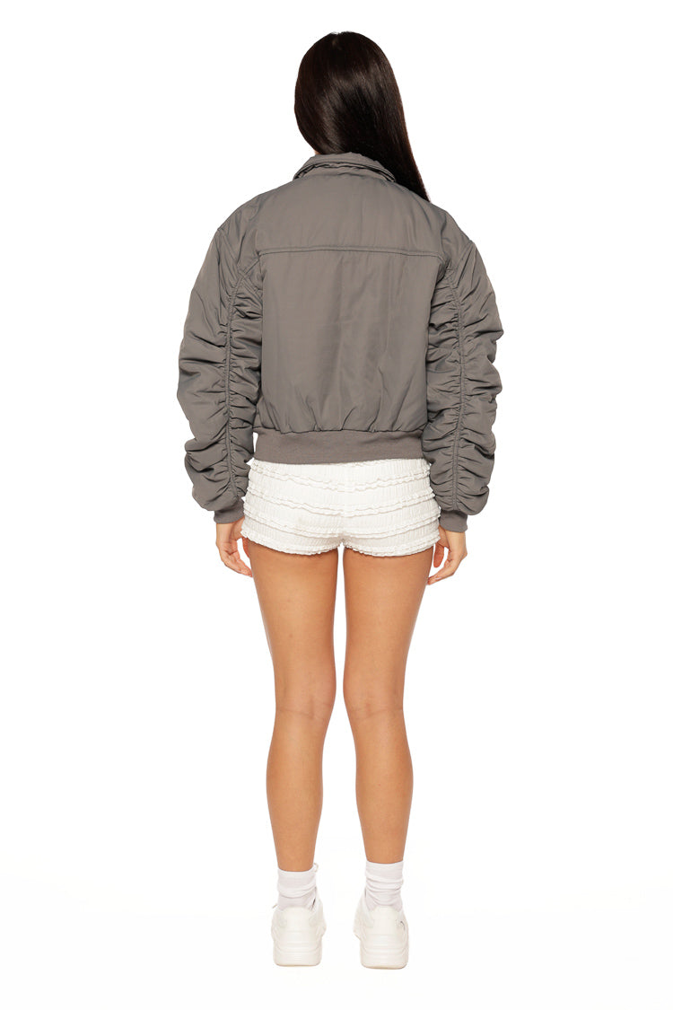 Rear view of a grey bomber jacket with ruched sleeves and a ribbed hem